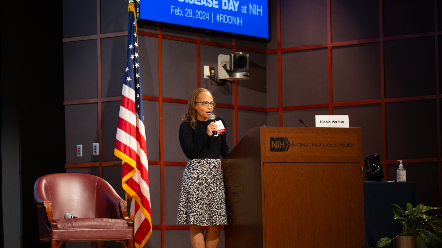 A woman speaking into a microphone while standing behind a lectern